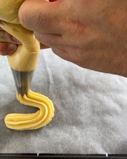 Una persona sta stendendo la glassa gialla a forma di lettera s