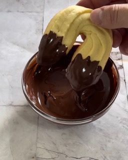 Una persona sta immergendo un biscotto nella salsa al cioccolato