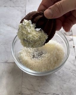 Una persona sta immergendo un biscotto al cioccolato in una ciotola di formaggio