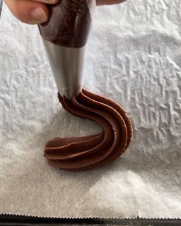 Una persona sta versando la glassa al cioccolato su un pezzo di carta oleata.
