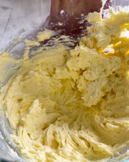 Una persona sta mescolando il burro in una ciotola con una spatola.