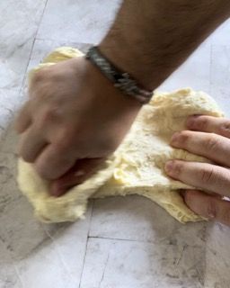 Una persona che indossa un braccialetto sta impastando un pezzo di pasta