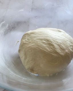 Una palla di pasta è posta in una ciotola di vetro.