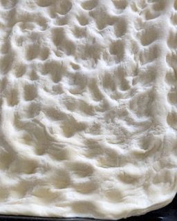 Primo piano di un pezzo di pasta per pizza su una teglia.