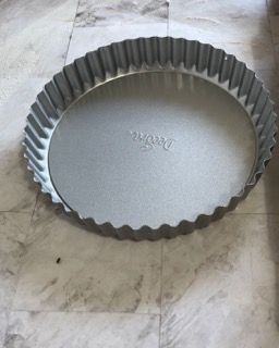 Una teglia per torta è appoggiata su un pavimento piastrellato