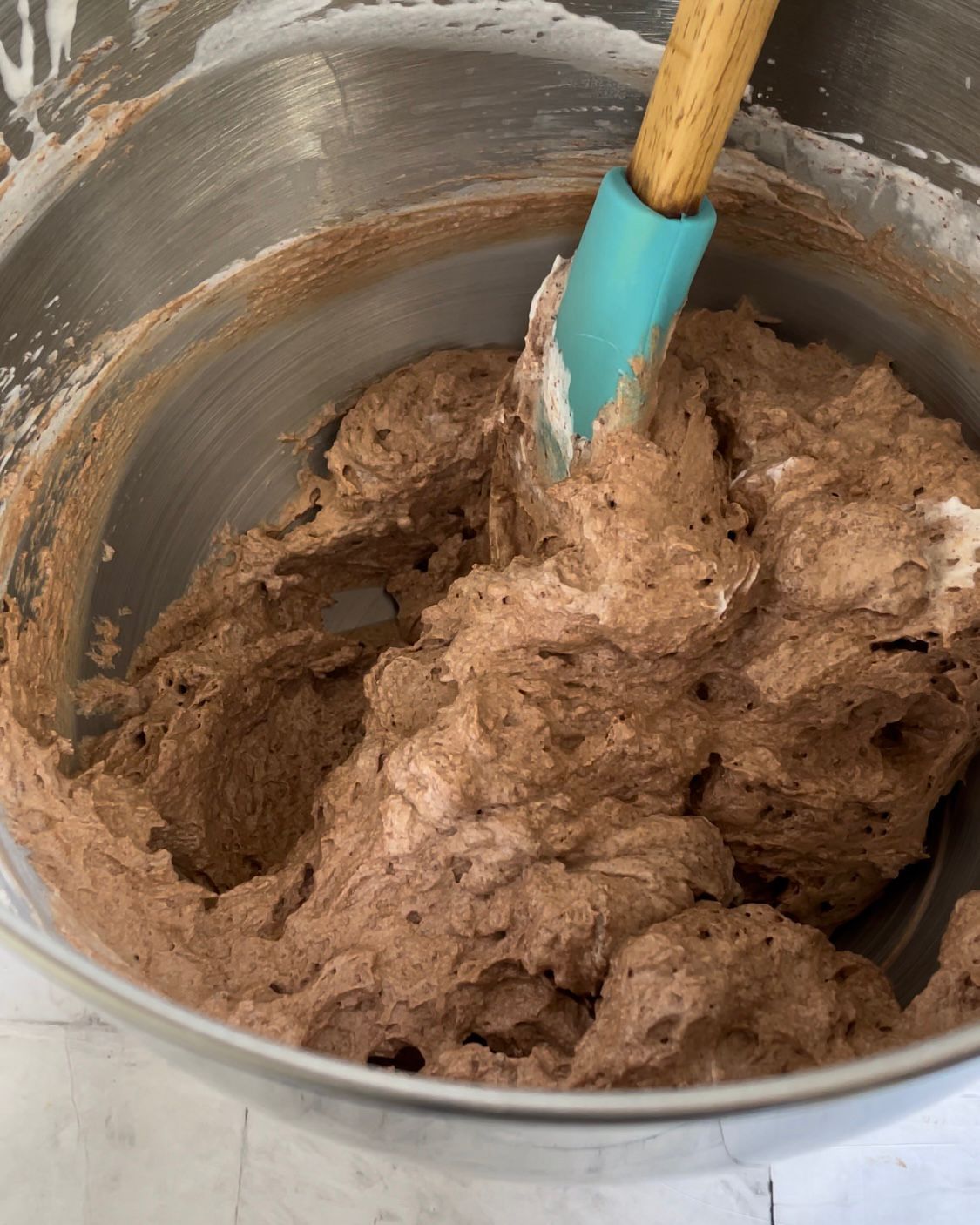 Una ciotola di glassa al cioccolato con una spatola dentro.