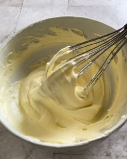 Una ciotola di panna montata con una frusta dentro.