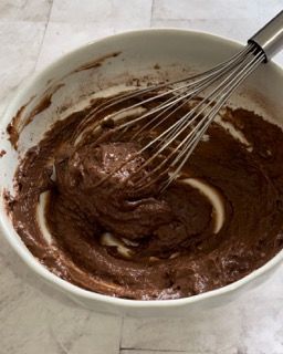 Una ciotola di pastella al cioccolato con una frusta dentro