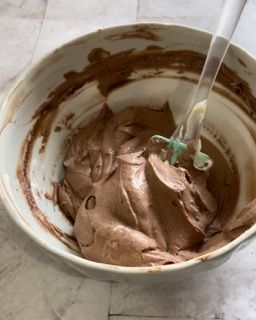 Una ciotola di glassa al cioccolato con una spatola dentro