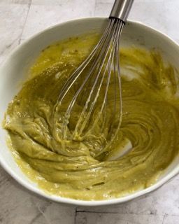 Una ciotola di salsa verde con una frusta dentro.