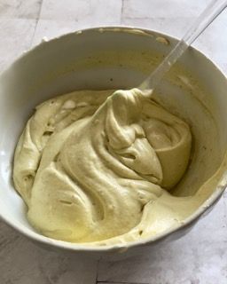 Una ciotola di glassa gialla con un cucchiaio dentro.