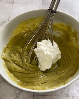 Una ciotola di salsa verde con panna montata e una frusta