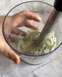 Una persona sta mescolando qualcosa in un bicchiere con un frullatore