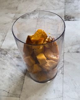 Un bicchiere pieno di pezzi di frutta su un pavimento piastrellato