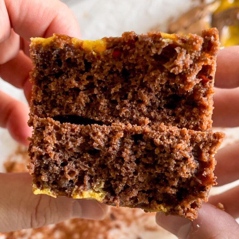 Una persona tiene in mano un pezzo di brownie con un morso staccato