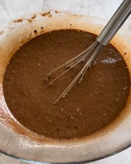 Una ciotola di liquido marrone con una frusta dentro