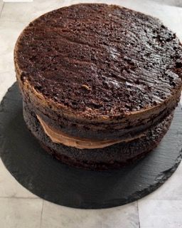 Una torta al cioccolato è disposta una sopra l'altra su un piatto di ardesia.