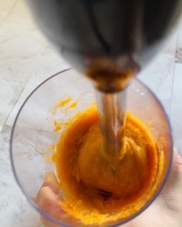 Una persona versa del liquido in un bicchiere da un frullatore.