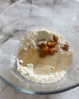 Una ciotola di vetro piena di farina e liquido su un tavolo.