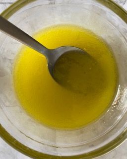 Una ciotola di liquido giallo con un cucchiaio dentro