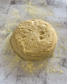 Una palla di pasta è appoggiata su un tavolo ricoperto di farina.