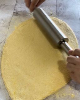 Una persona sta stendendo la pasta con un mattarello su un tavolo.