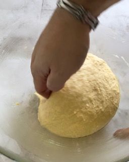 Una persona tiene in mano una palla di pasta in una ciotola.