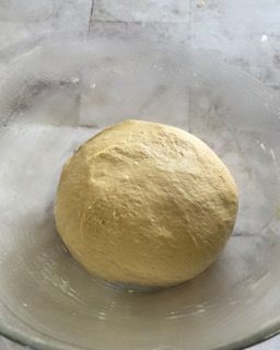 Una palla di pasta è posta in una ciotola di vetro.