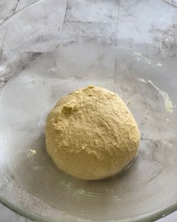 Una palla di pasta è posta in una ciotola di vetro.