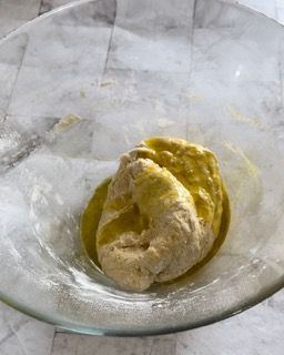 Una ciotola di vetro piena di impasto e olio su un tavolo.