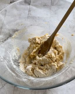 Una ciotola di impasto con un cucchiaio di legno dentro.