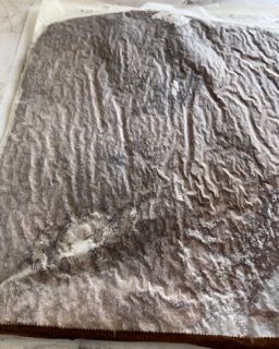 Un pezzo di torta al cioccolato è appoggiato su un foglio di carta oleata.
