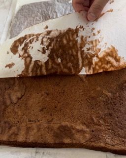 Una persona sta tagliando un pezzo di torta al cioccolato su un foglio di carta oleata.