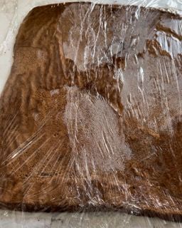 Un pezzo di torta al cioccolato avvolto nella pellicola trasparente su un tavolo.
