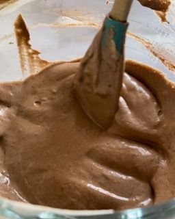 Una ciotola di glassa al cioccolato con una spatola dentro