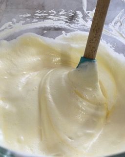 Primo piano di una ciotola di glassa bianca con una spatola dentro.