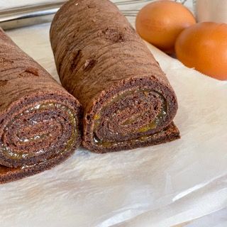 Due rotoli di cioccolato su un tavolo con le uova sullo sfondo