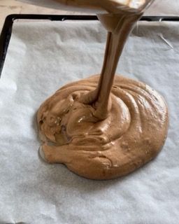 Un liquido marrone viene versato su un pezzo di carta oleata.