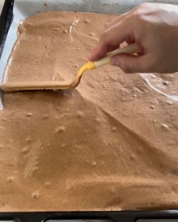 Una persona sta spargendo un liquido giallo su una superficie marrone.