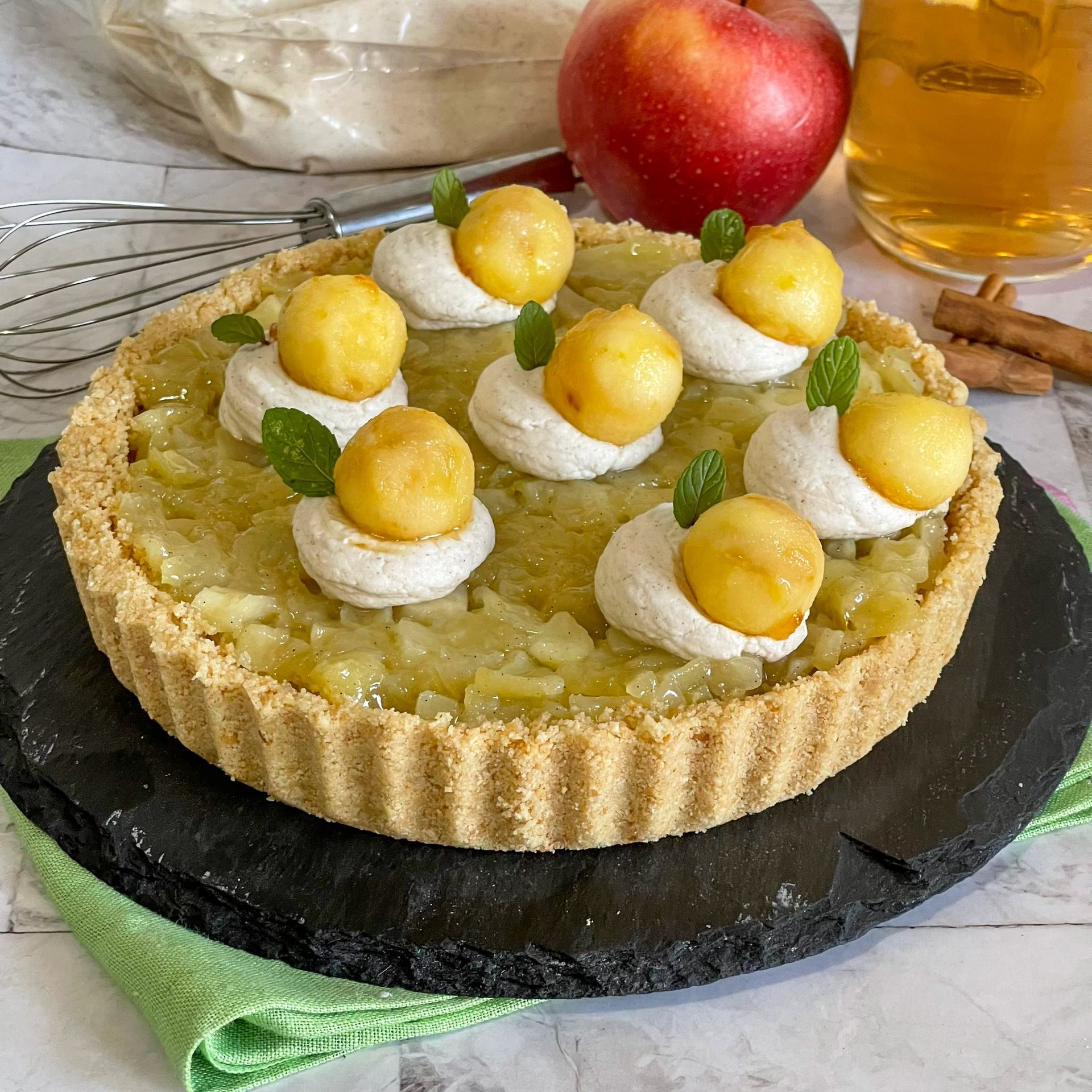 Una torta con mele e panna montata sopra è su un piatto nero.