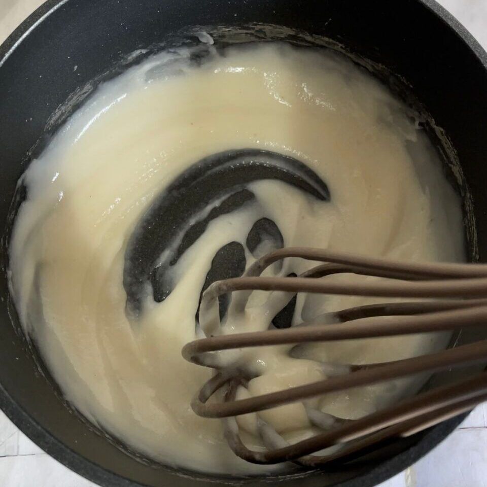 Una frusta è in una pentola di liquido bianco.