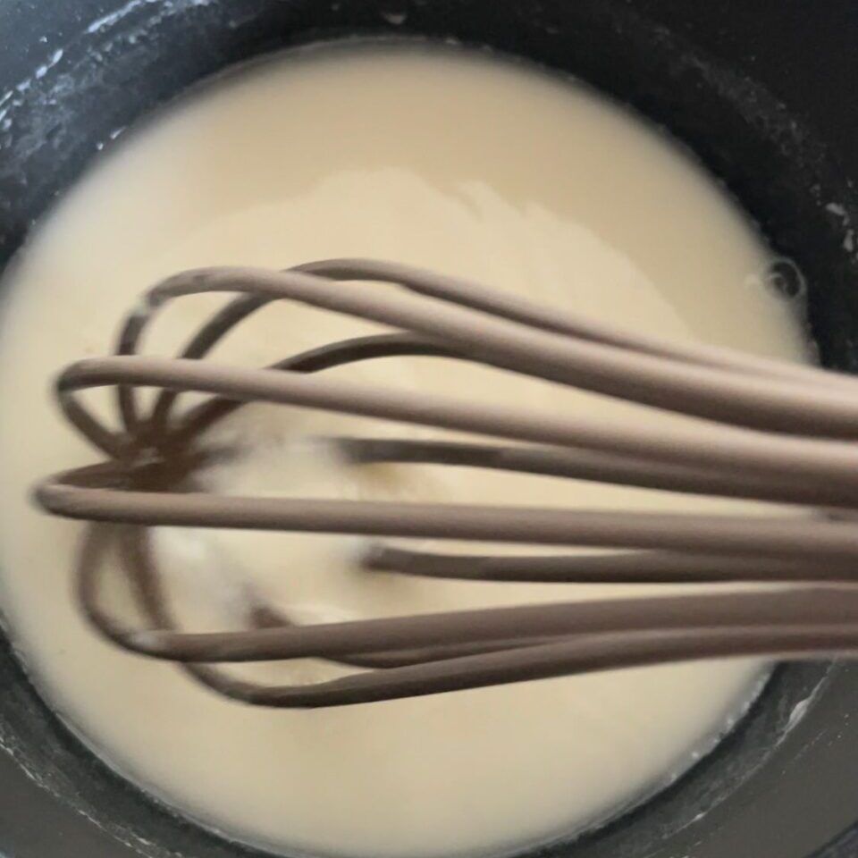 Un primo piano di una frusta in una pentola di liquido