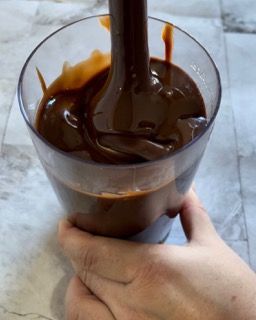 Una persona sta versando la salsa al cioccolato in un bicchiere