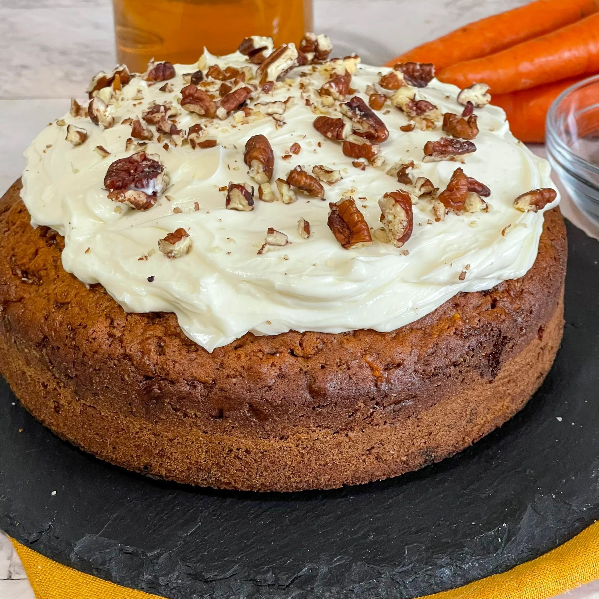Una torta di carote con glassa al formaggio cremoso e noci pecan sopra