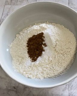Una ciotola bianca piena di farina e cannella su un tavolo.