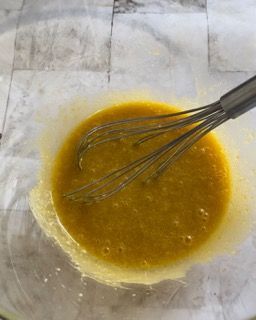 Una frusta è in una ciotola di liquido giallo.