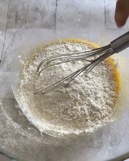 Una persona sta mescolando la farina in una ciotola piena di liquido.
