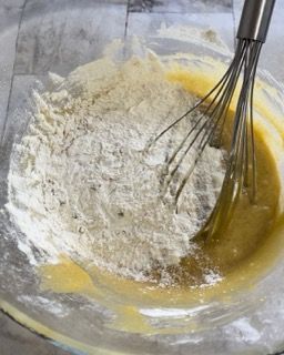 Una ciotola di pastella con farina e una frusta dentro.
