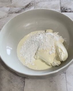 Una ciotola bianca piena di panna montata e zucchero a velo.