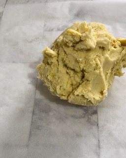 Una palla di pasta è appoggiata su un pezzo di carta oleata.